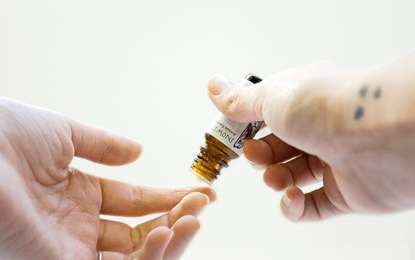 closeup of hands applying skincare oil to fingertip
