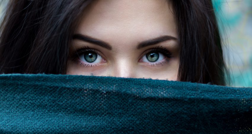 closeup of woman's eyes, face hiding behind fabric