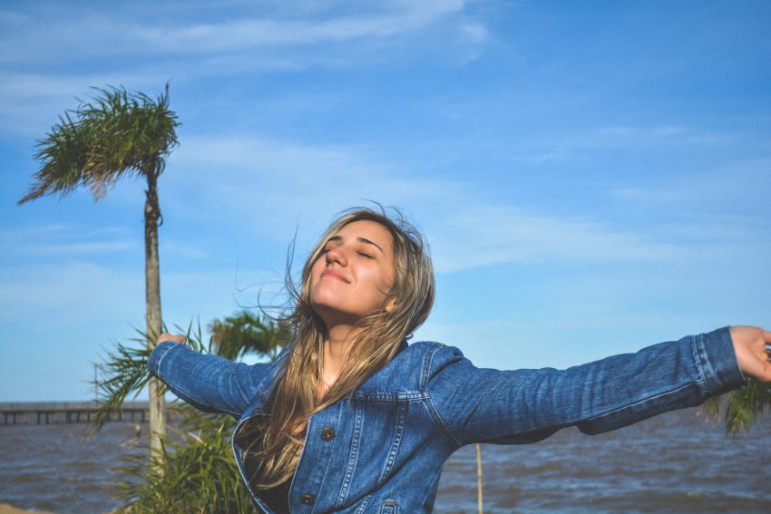 happy person outside, arms outstretched, destressing tips