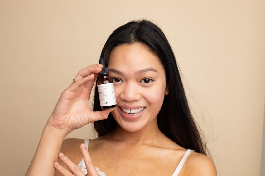 person holding skincare bottle next to face, smiling at camera, how to tell if products have ceramides