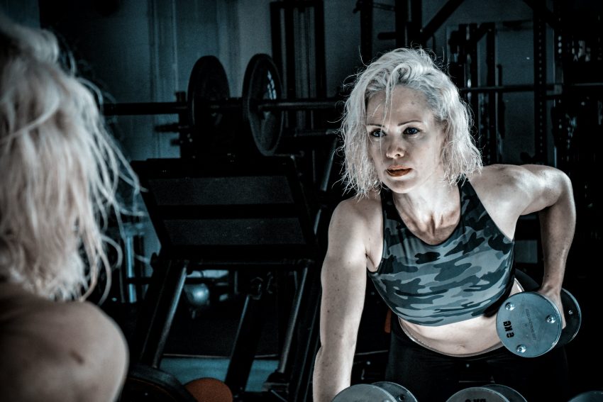 grey-haired woman lifting weights in gym