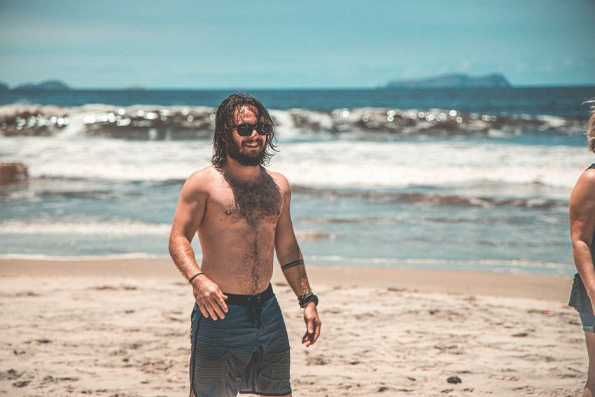 topless man at the beach wearing sunglasses