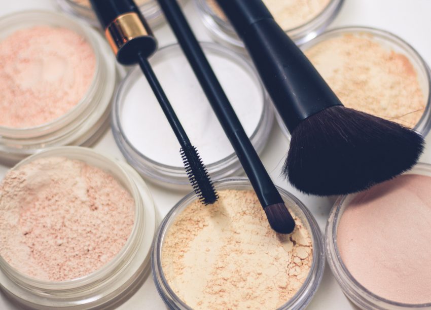 pots of makeup with brushes laid on top