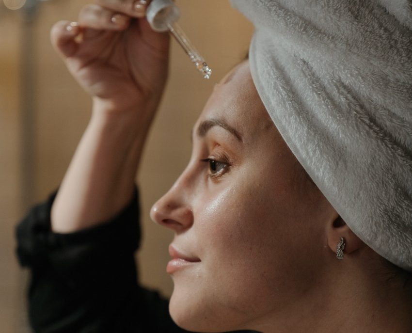 person wearing towel on head, applying niacinamide