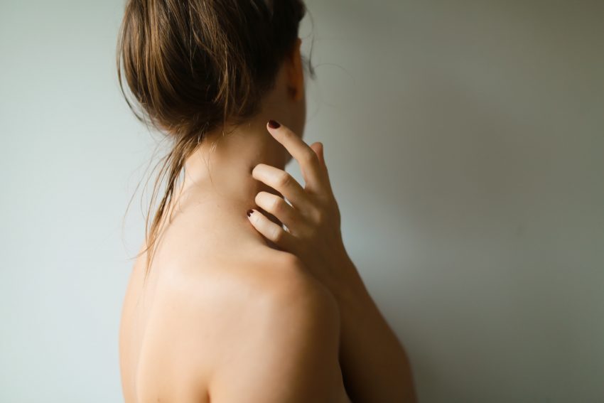 woman with bare skin touching her neck