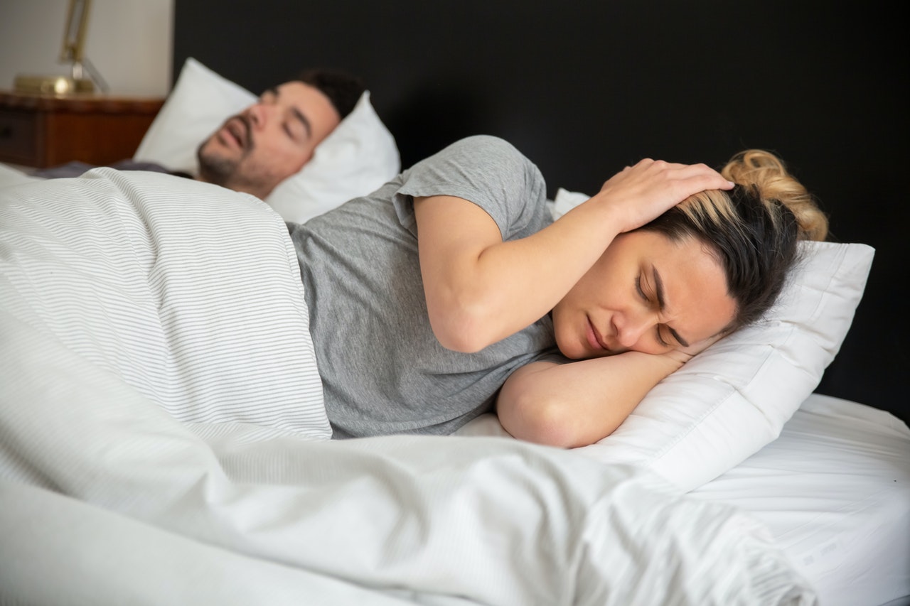 couple in bed, one snoring, other struggling to sleep