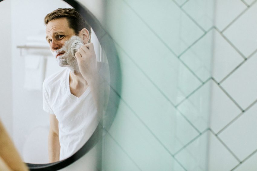 reflection of man applying shaving cream
