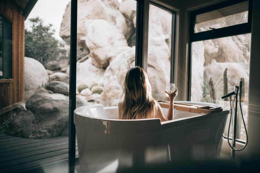woman sitting in bathtub with wine glass